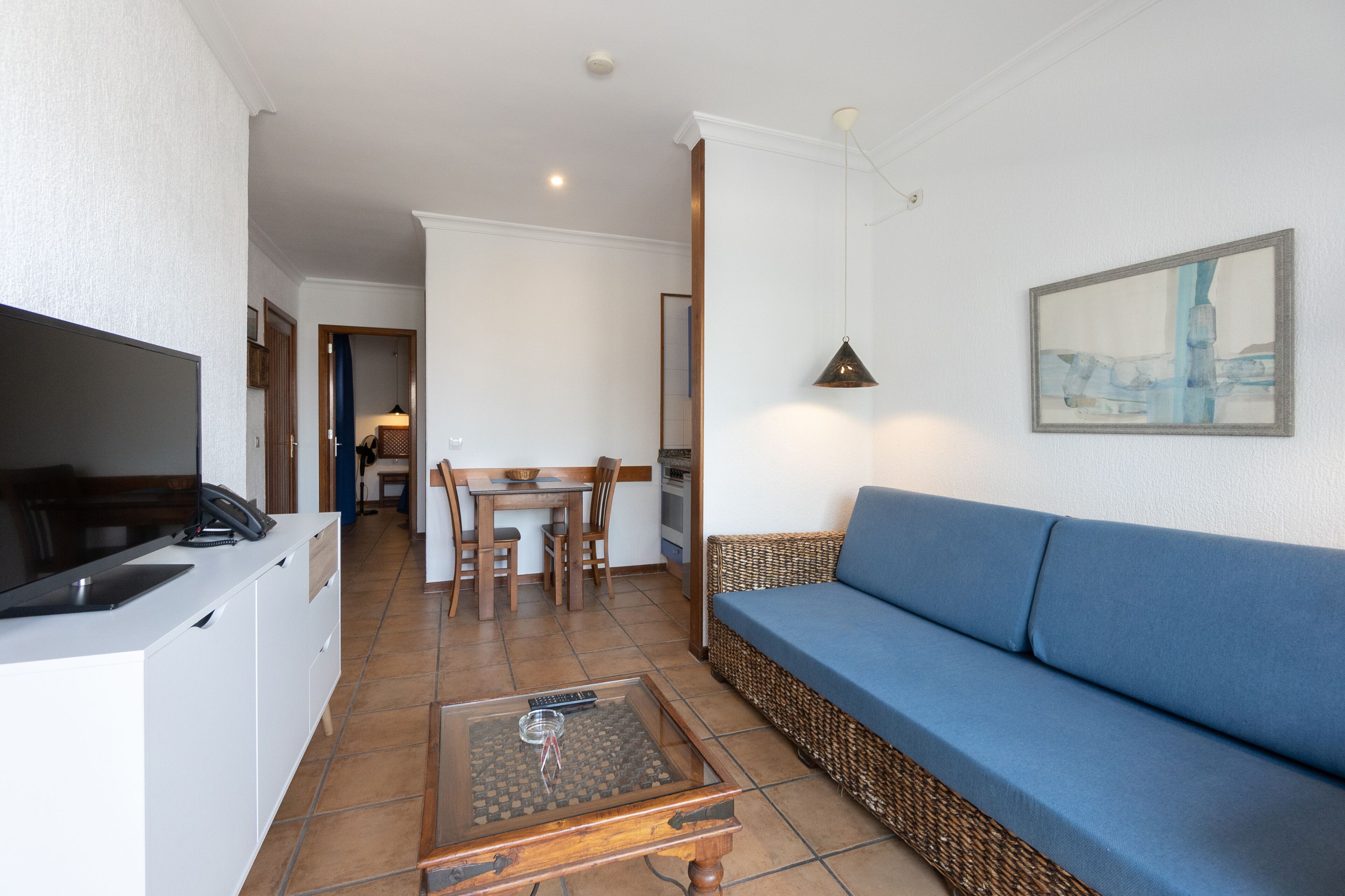 Una sala de estar con un sofá, una mesa de centro y una mesa de comedor con sillas.