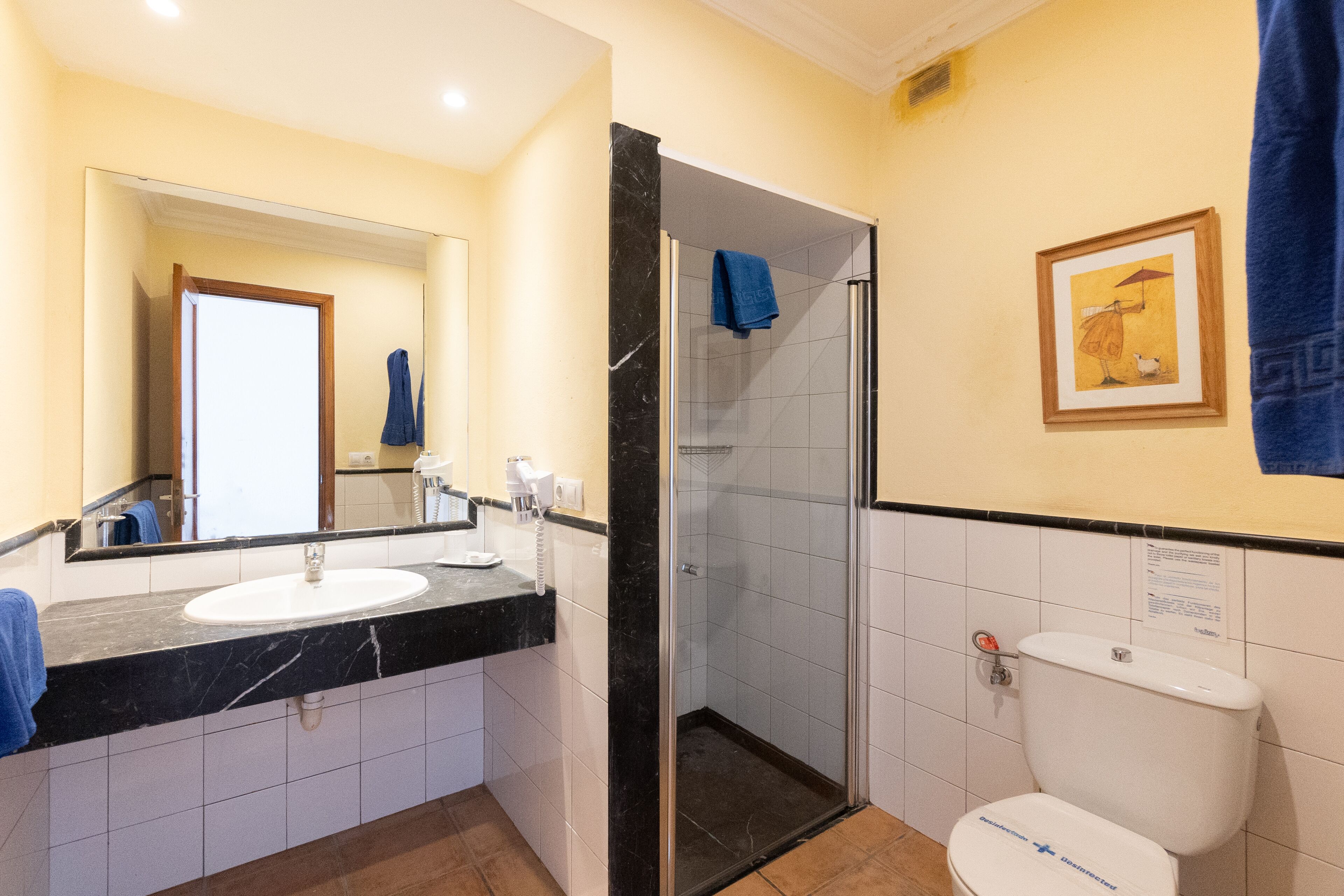 A bathroom with a double sink, a glass shower enclosure, and a toilet.