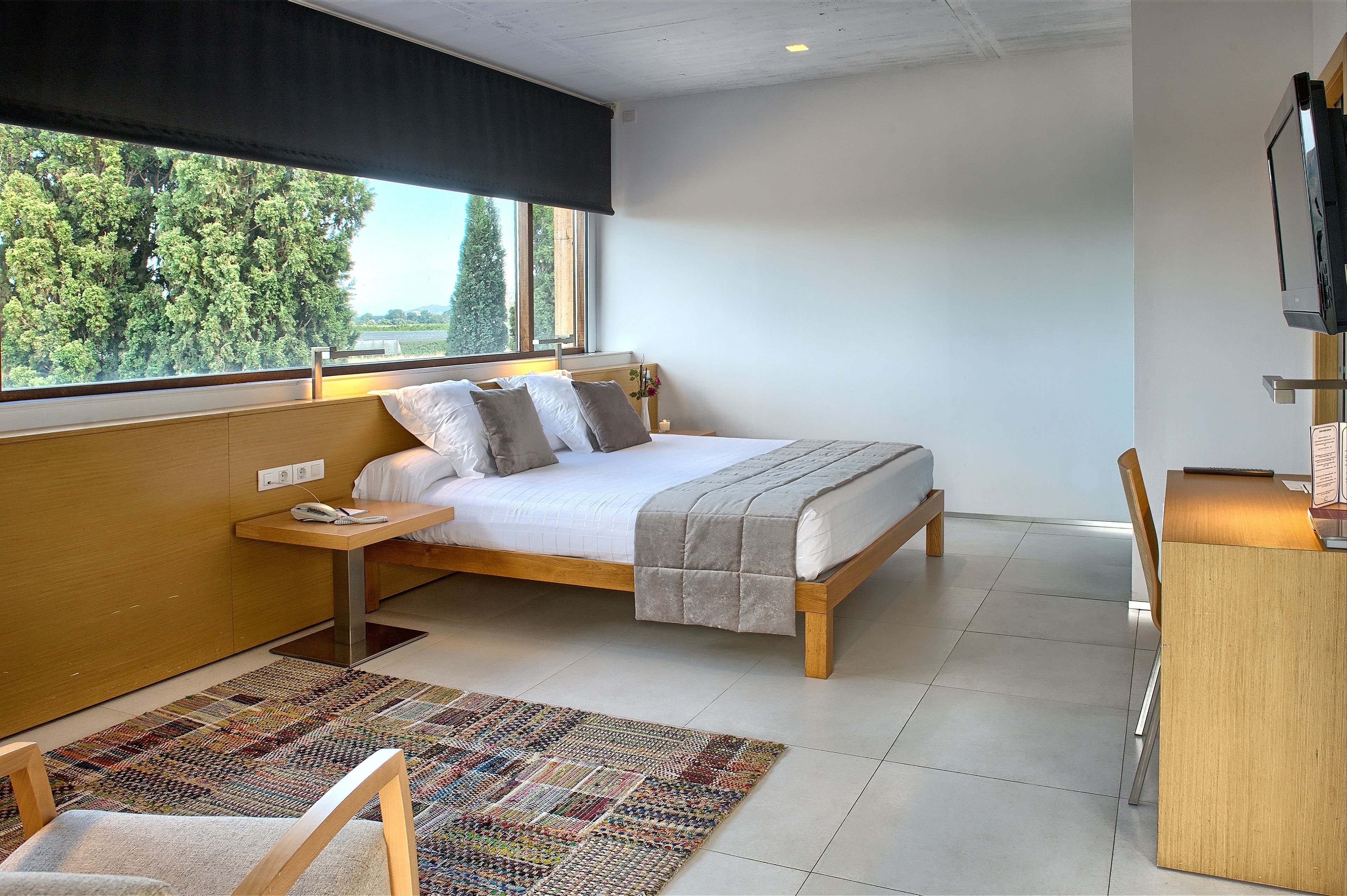 A bedroom with a bed, bedside table, and a desk with a chair.