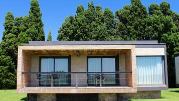 A modern building with a flat roof, large windows, and a balcony with glass railings.