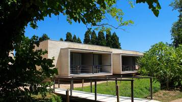 A modern building with a flat roof, large windows, and a covered outdoor area with a metal railing.