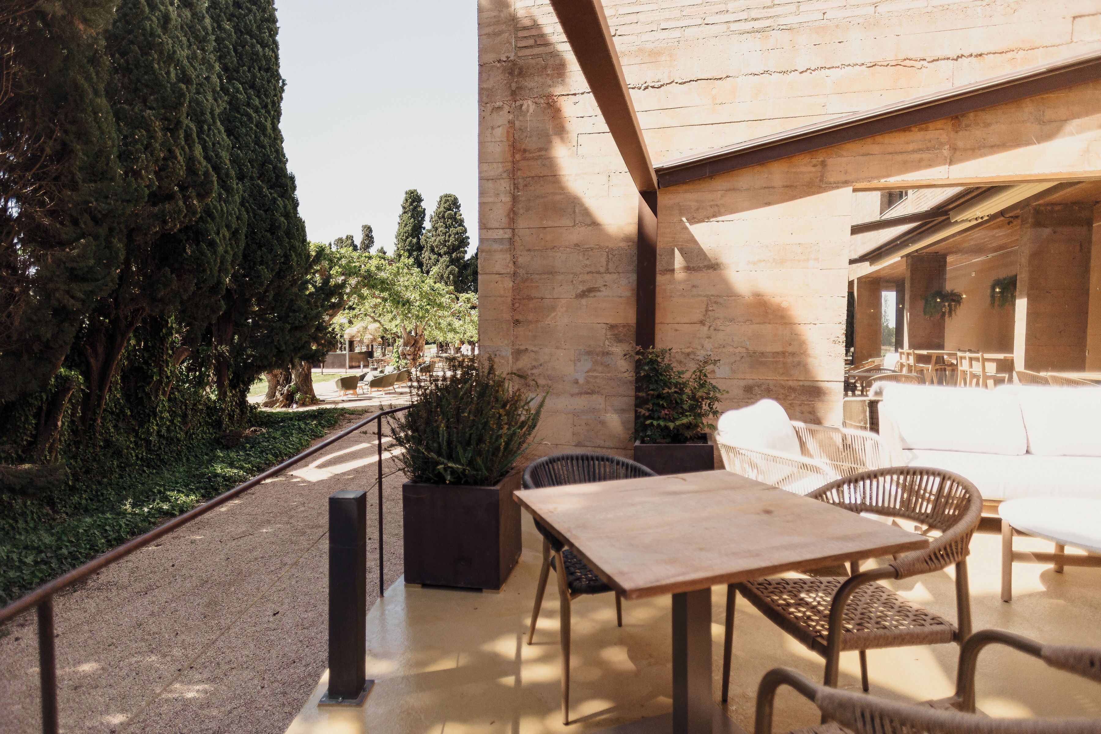 An outdoor seating area with a table and chairs, surrounded by stone walls and potted plants.