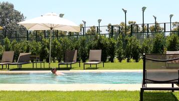 Una piscina al aire libre, sombrillas, tumbonas