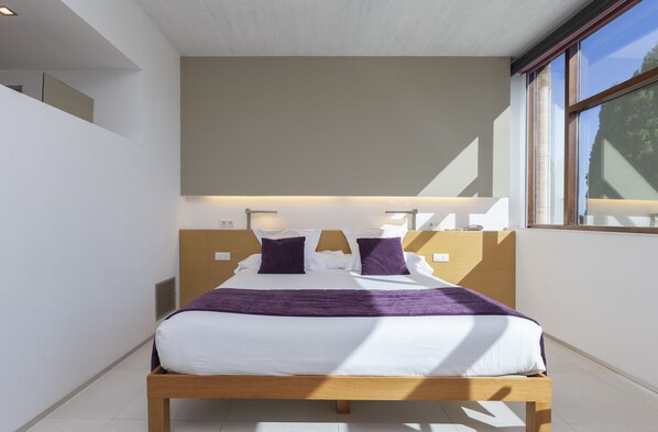 A modern bedroom with a wooden bed, white bedding, and a purple throw.