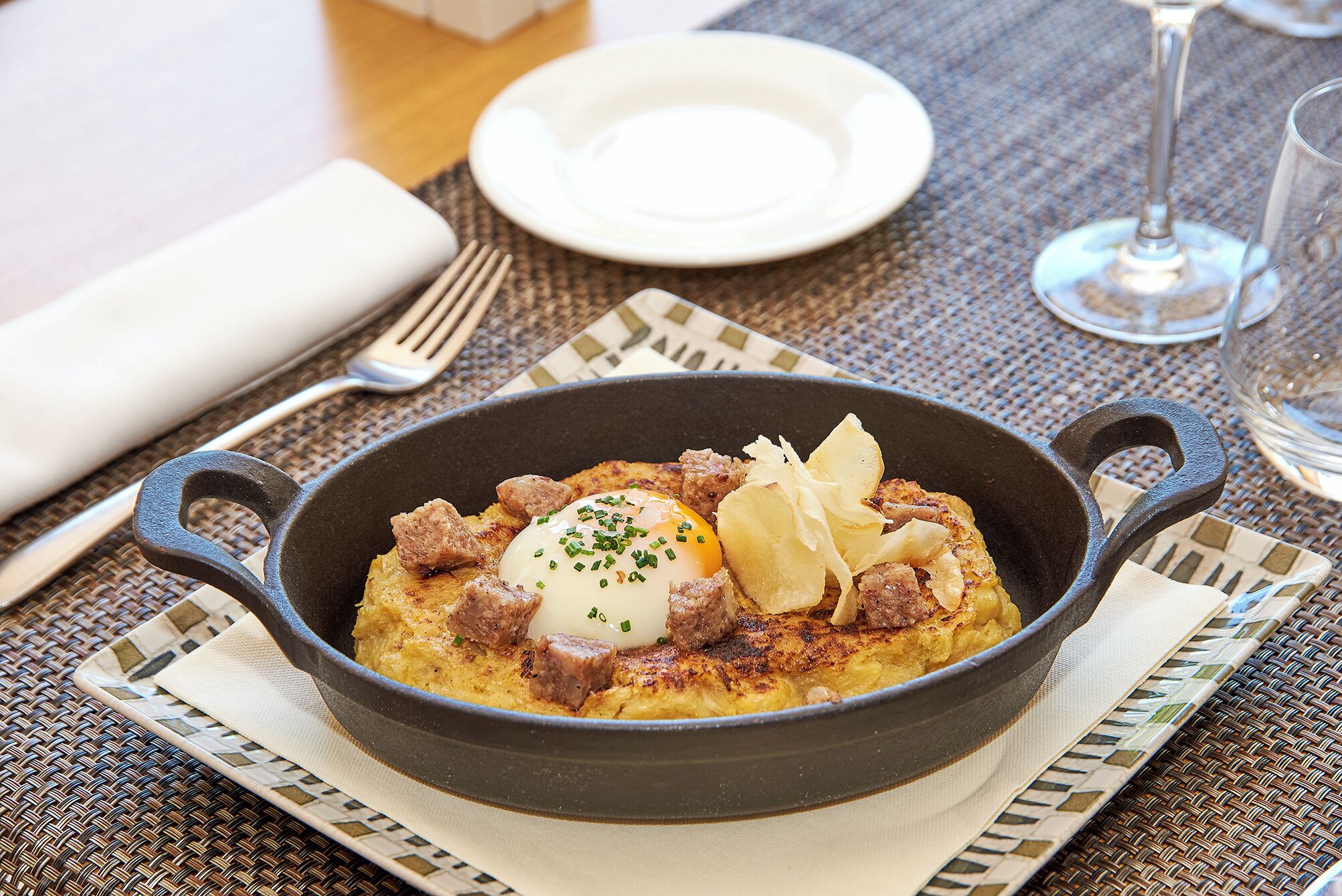 Un plato para el desayuno en una sartén de hierro fundido sobre un mantel tejido.