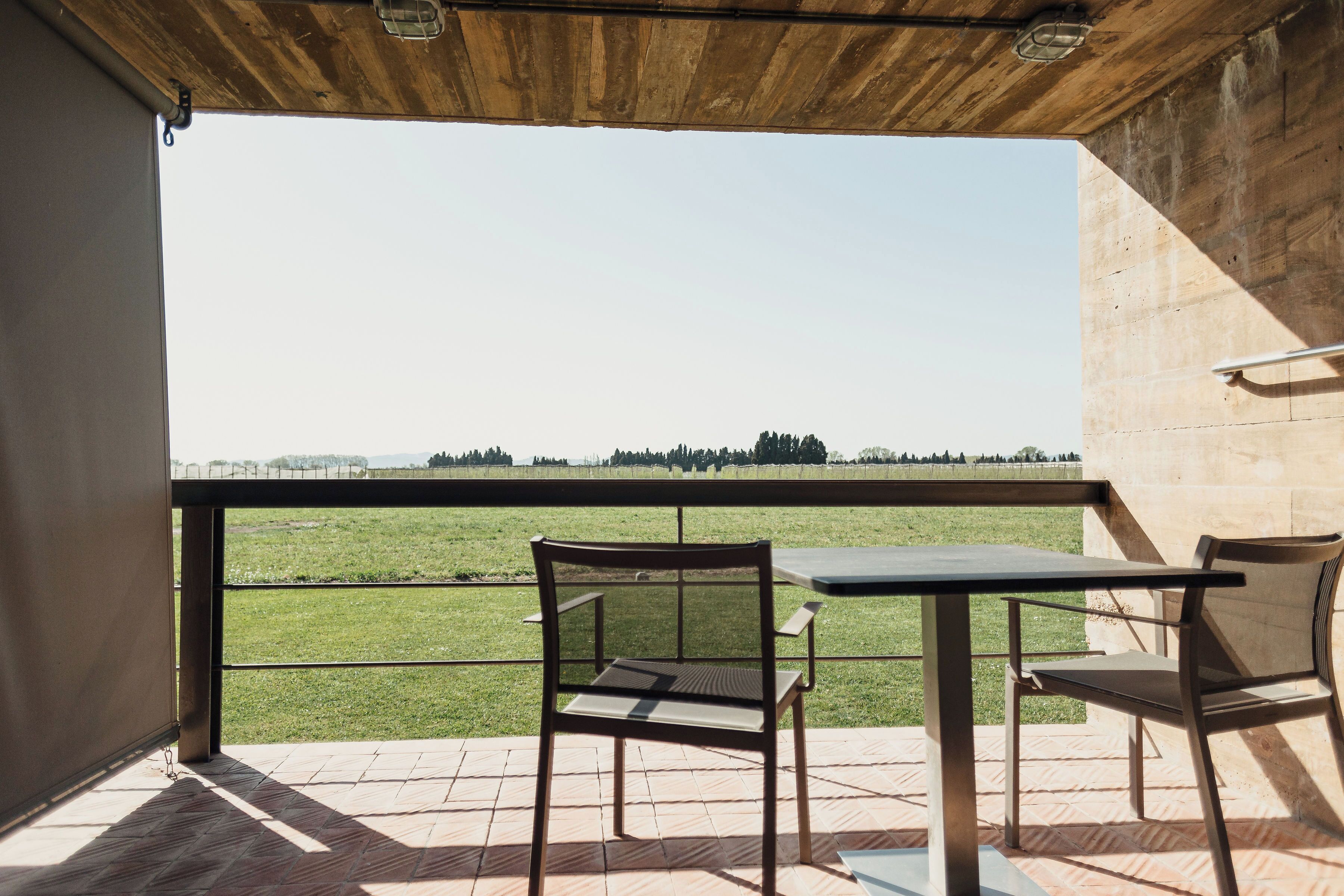Een balkon met uitzicht op een grasveld, twee stoelen en een tafel.