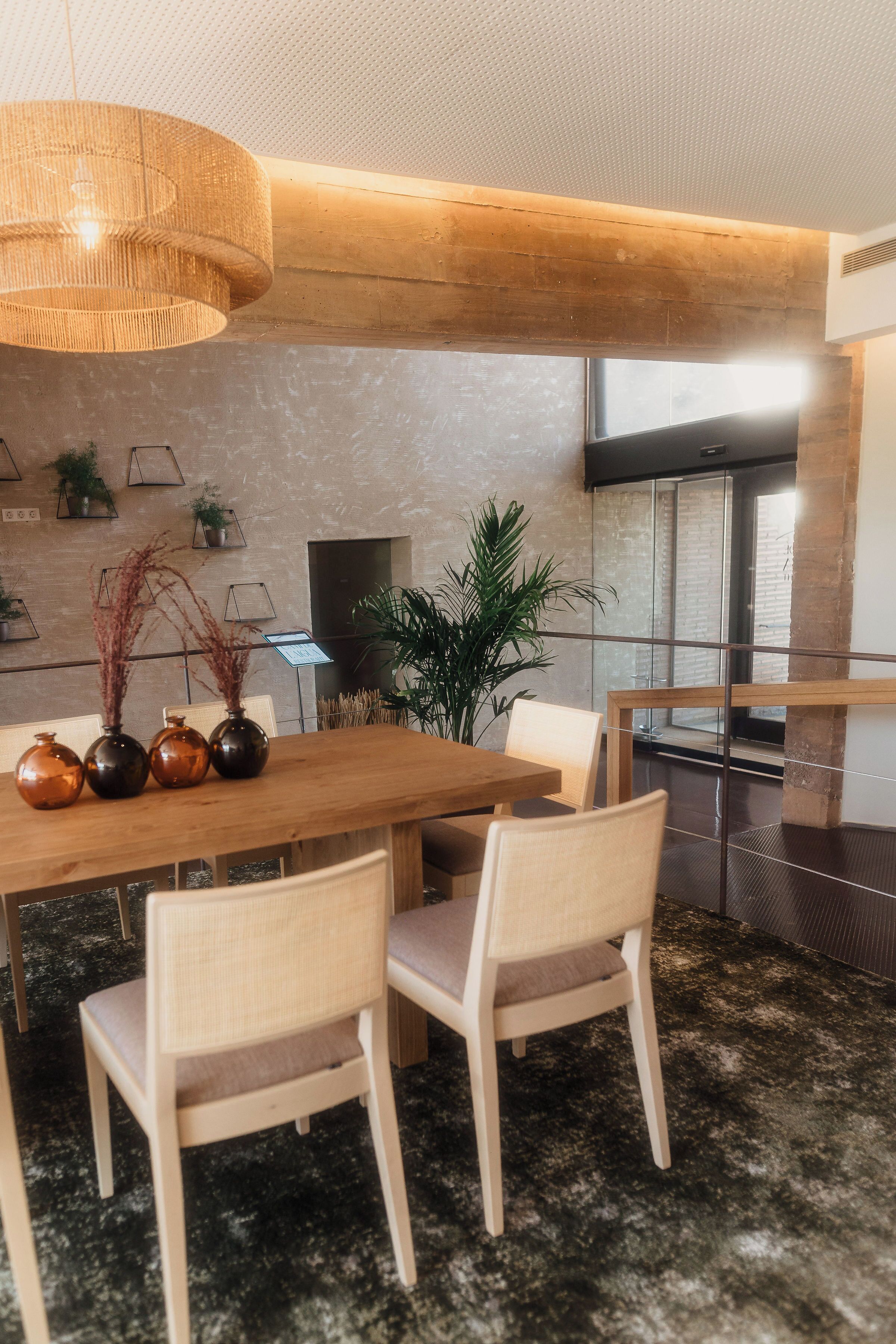 A modern dining area with a wooden table, four chairs, and a hanging light fixture.