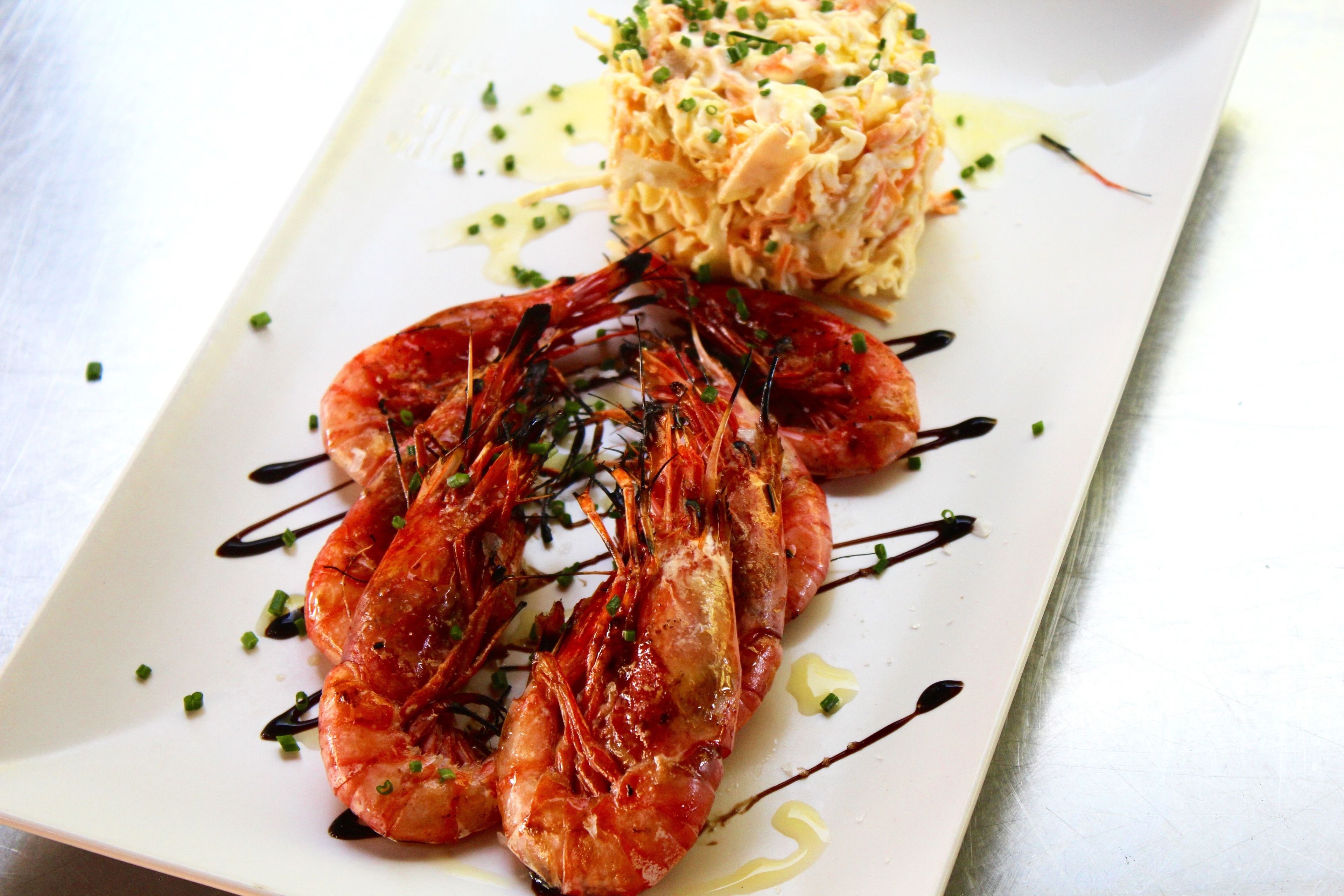 Un plato de camarones a la parrilla con una guarnición de ensalada de repollo.