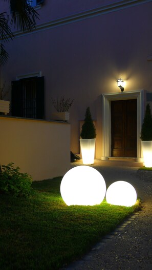 A well-lit entrance with a door, two large illuminated spheres, and potted plants.
