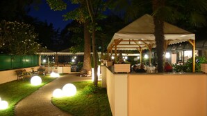 An outdoor dining area with tables and chairs, a covered seating area, and a pathway. - Locanda delle Corse (Rome)