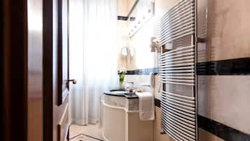 A modern bathroom with a curved shower, a white sink, and a towel rack.