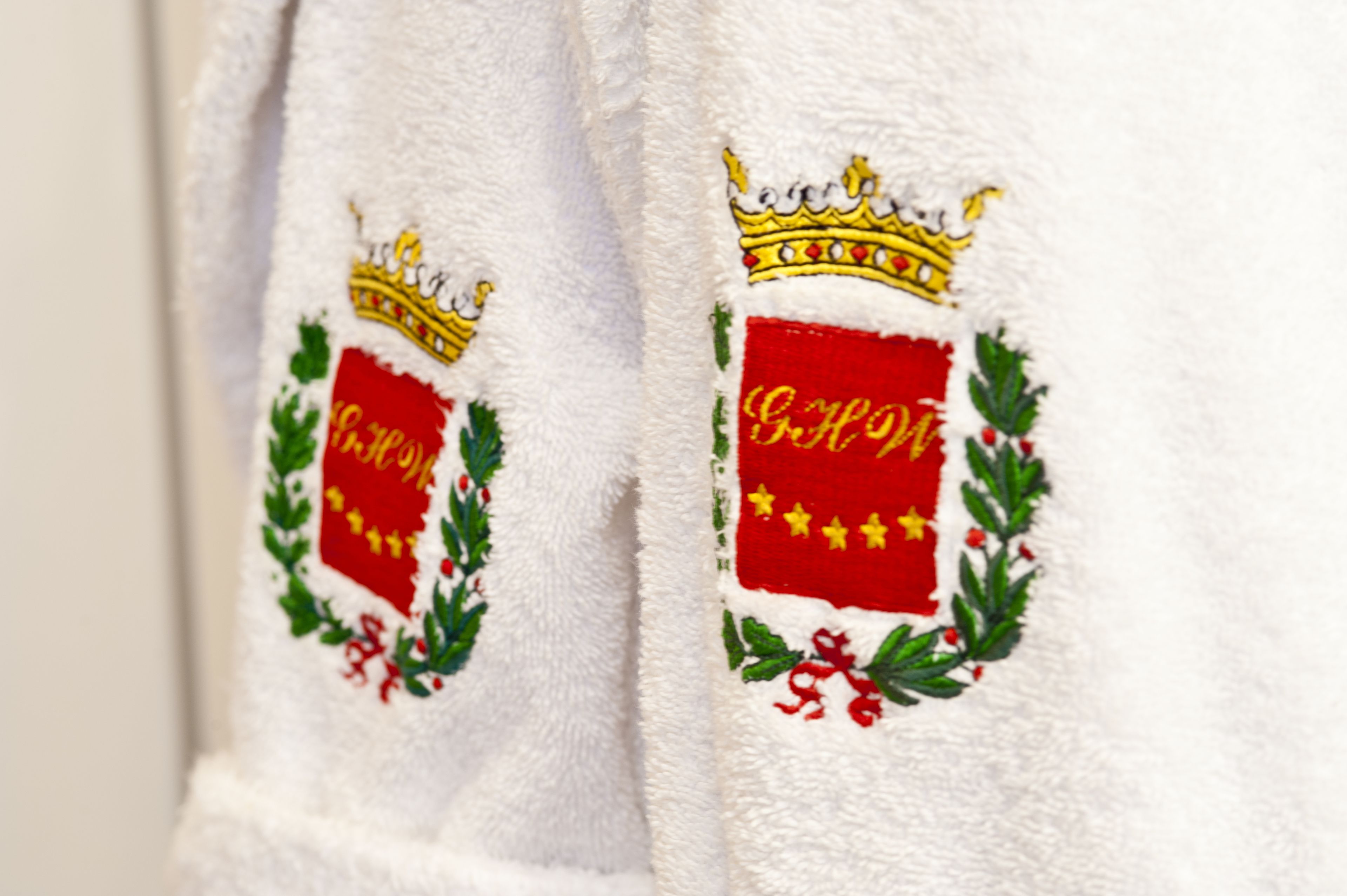 A white towel with embroidered royal symbols and text.