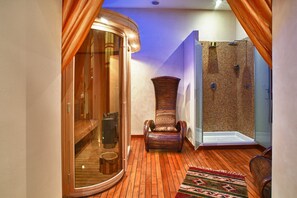 Un sauna con banca de madera, un jarrón grande y una zona de ducha con paredes de vidrio.