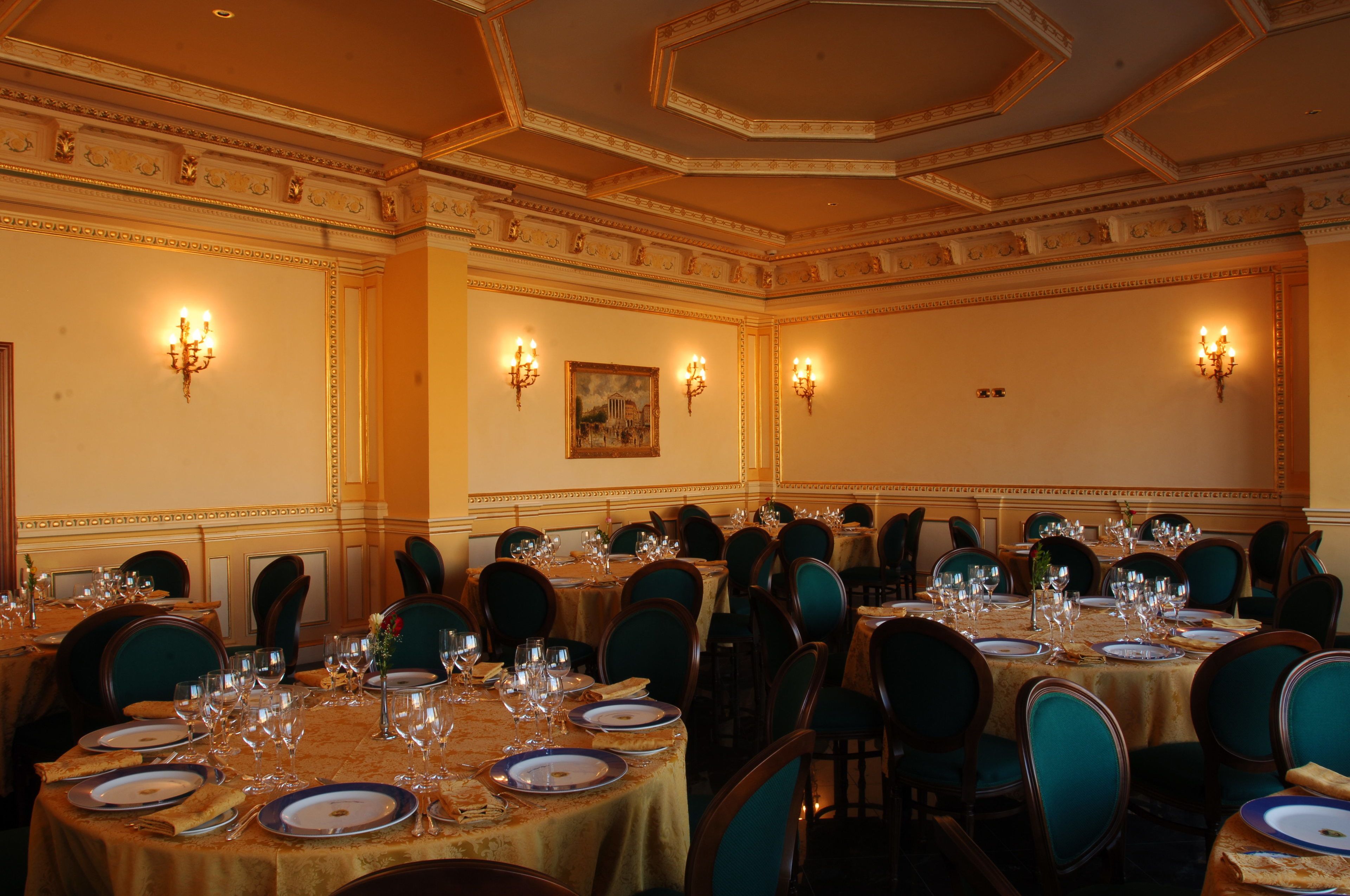 A formal dining room with multiple tables set for a meal, each with chairs and table settings.