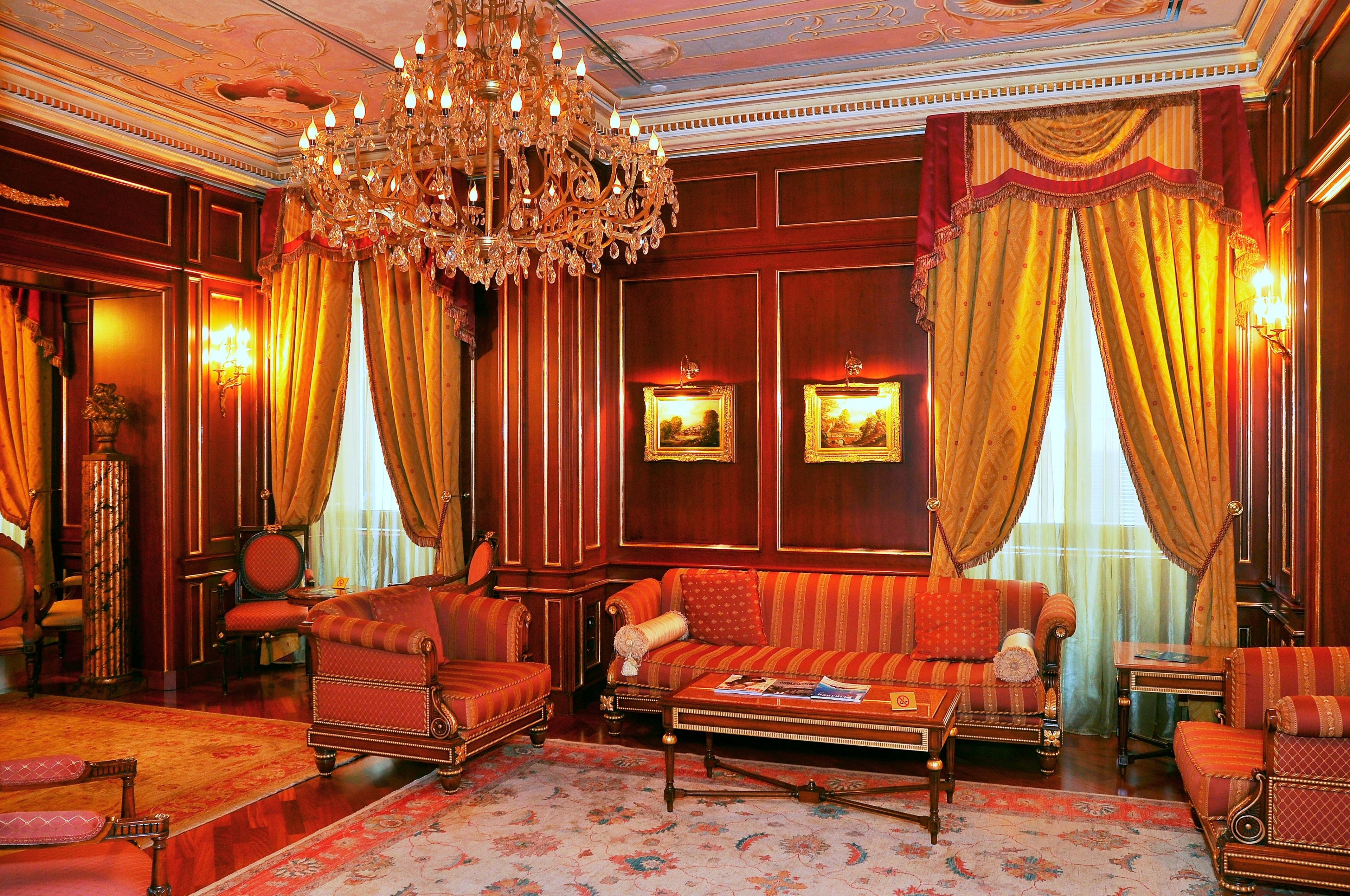 Un'elegante stanza con un grande lampadario, tende preziose e arredi classici.