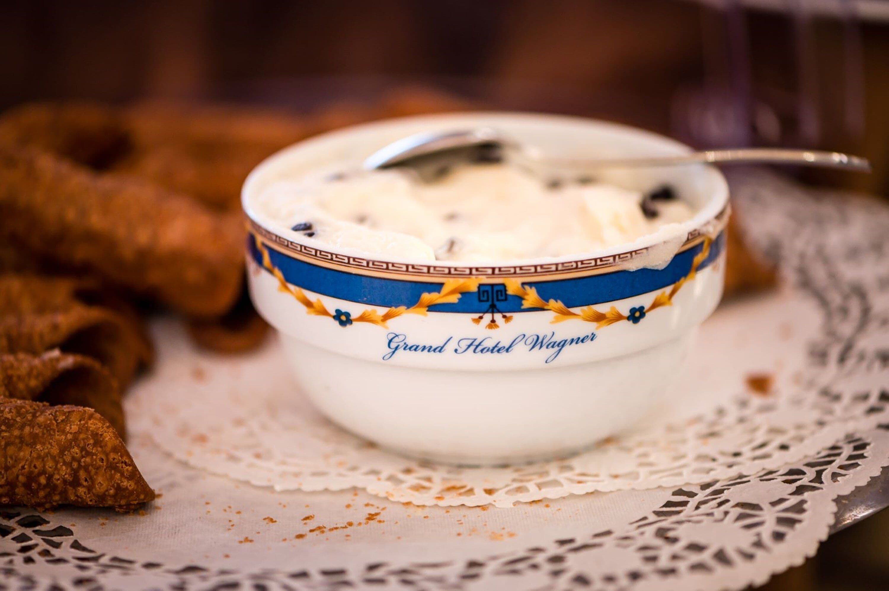 A bowl of yogurt with a spoon, placed on a lace doily.