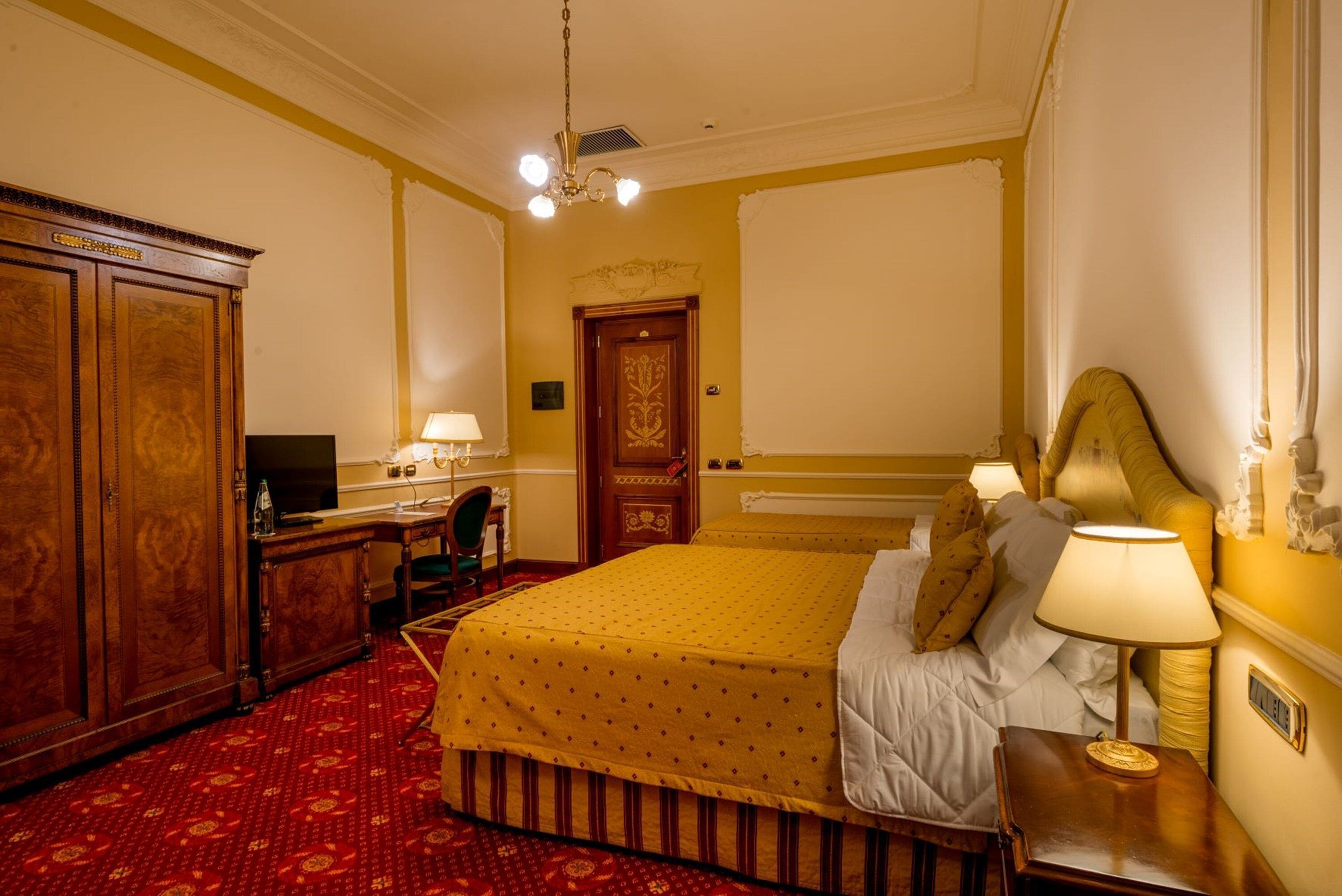 Une chambre d’hôtel avec un grand lit, une armoire en bois, un bureau avec une lampe et un téléviseur.