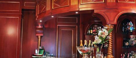 A bar area with a chandelier, wooden paneling, a bar counter, and a seating area with a table and chairs.