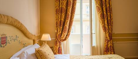 Une chambre d’hôtel avec un lit, une table de chevet avec une lampe et une fenêtre avec des rideaux.