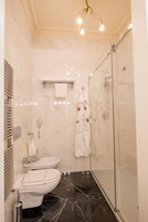 Une salle de bain moderne équipée de toilettes, d’un bidet et d’une douche à parois de verre.