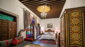 A traditional room with a bed, a sofa, a small table, and a patterned floor. - Riad dar Chrifa (Fes)