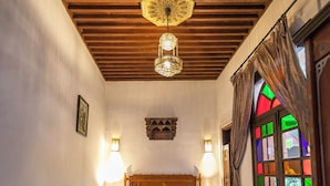 A room with two beds, a wooden ceiling, a patterned floor, and a stained glass window. - Riad dar Chrifa (Fes)