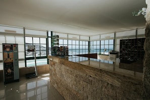 A modern interior with a stone counter, large windows offering a view of the sea, and a vending machine. - Servatur Montebello (Mogan)