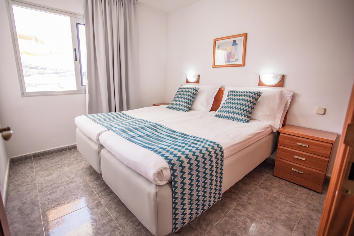 A neatly arranged bedroom with a large bed, a bedside table, and a nightstand.