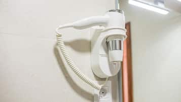 Un dispositivo blanco fijado a la pared, con un cable enrollado, una punta metálica y una toma de corriente.