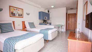 Een hotelkamer met twee bedden, een kitchenette, een eethoek en een televisie.