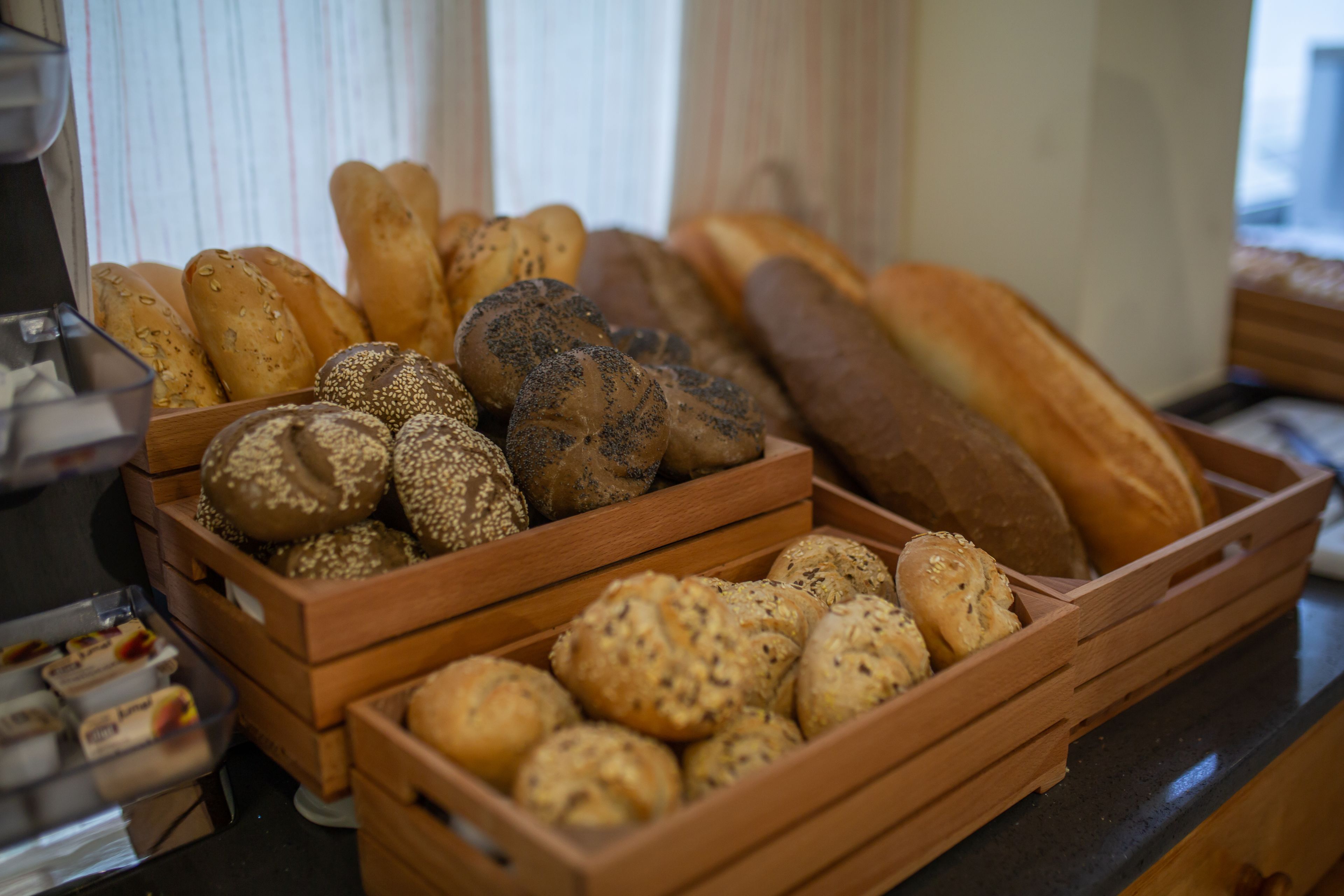 A variety of breads in wooden baskets on a counter.