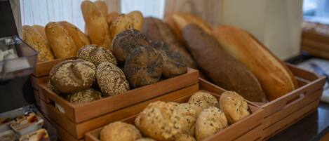 A variety of breads in wooden baskets on a counter.