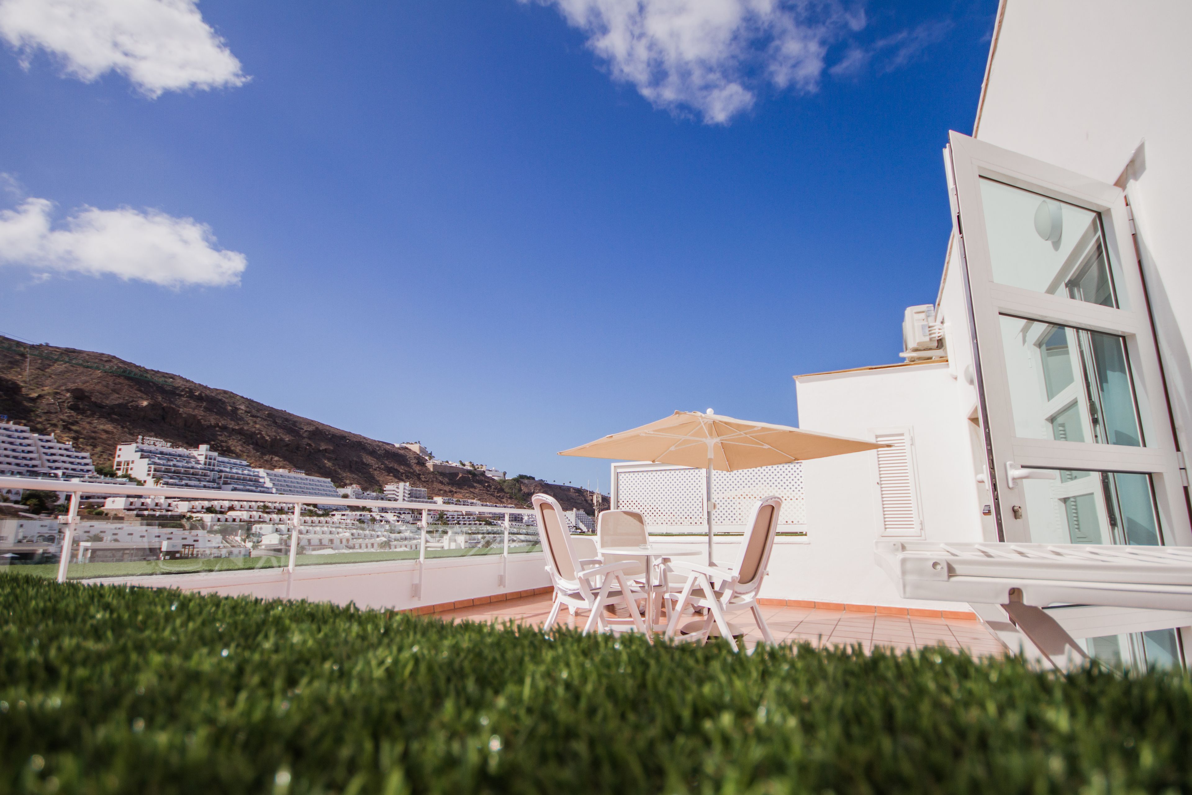 Una terraza con mobiliario exterior y vistas a un paisaje montañoso.