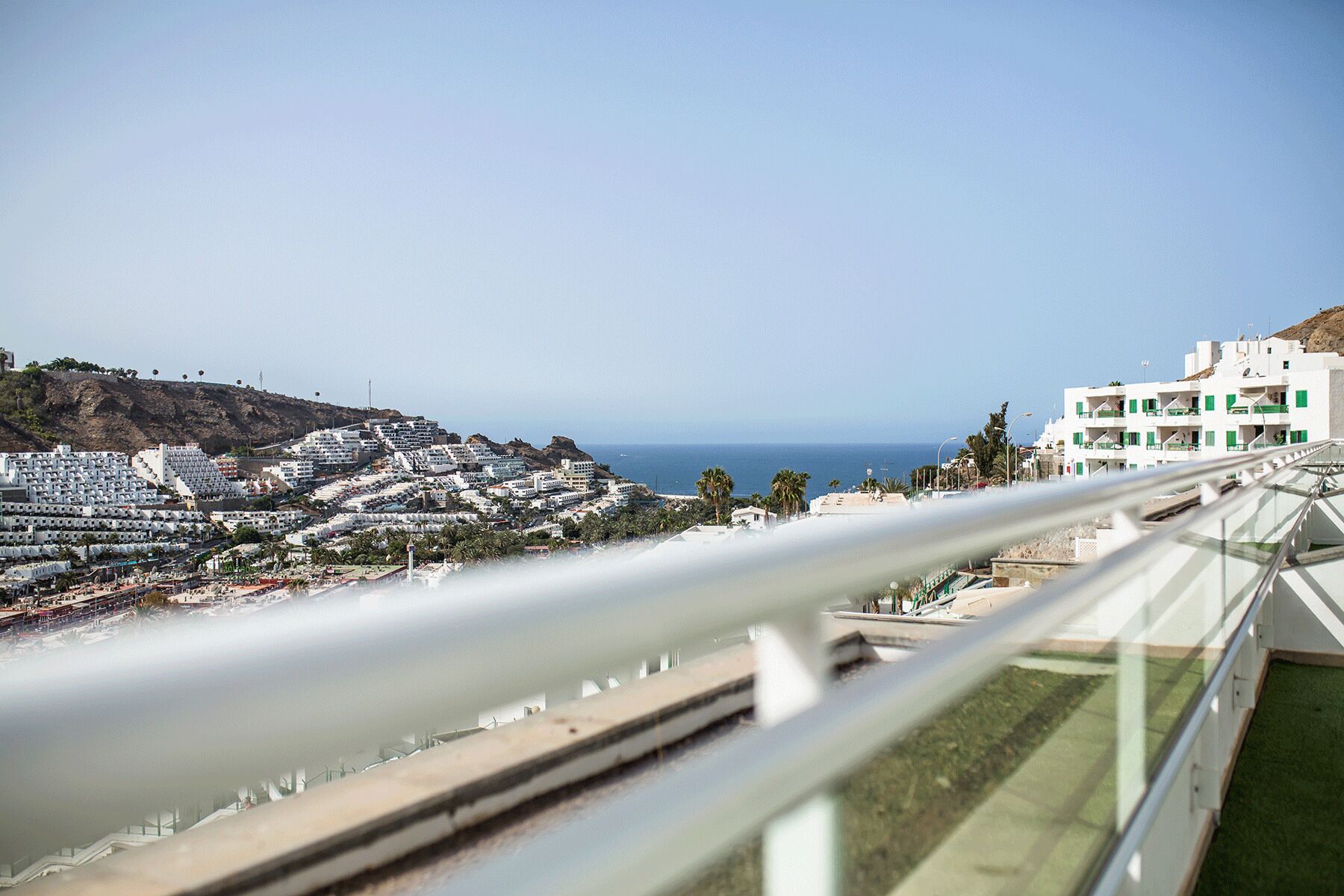 Eine Küstenstadt mit Blick auf das Meer, mit einer Mischung aus Wohnhäusern und einem markanten weißen Gebäude mit grünen Fensterläden.