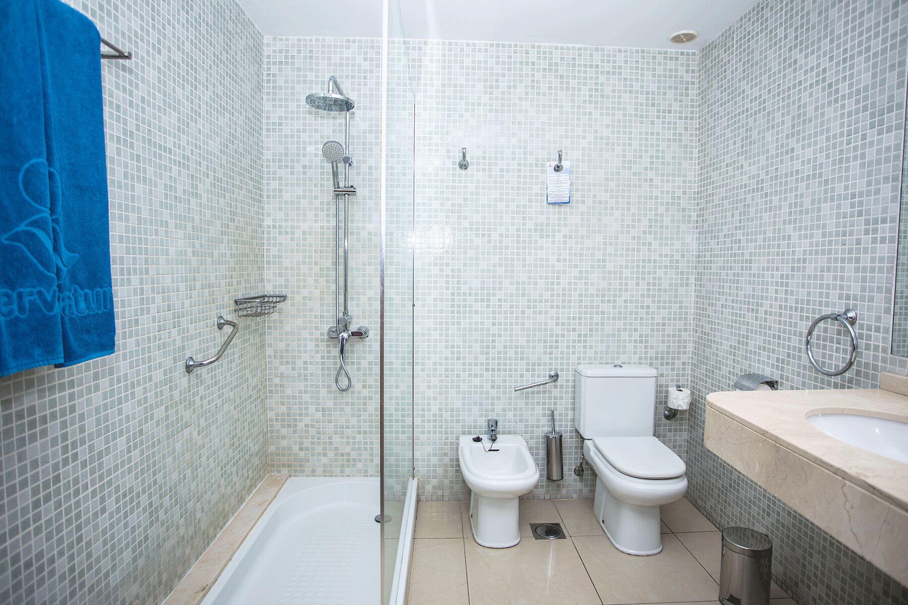 Un baño con ducha, bidé, inodoro y lavamanos.