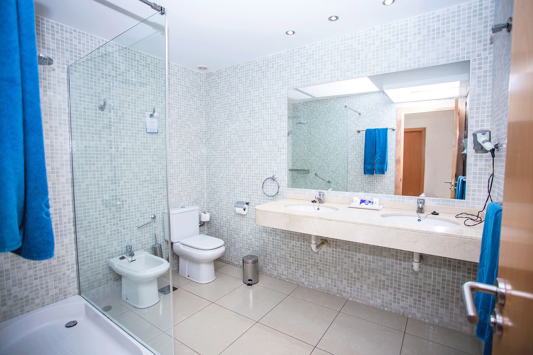Un baño moderno con cabina de ducha de vidrio, inodoro, bidé y lavamanos con espejo.