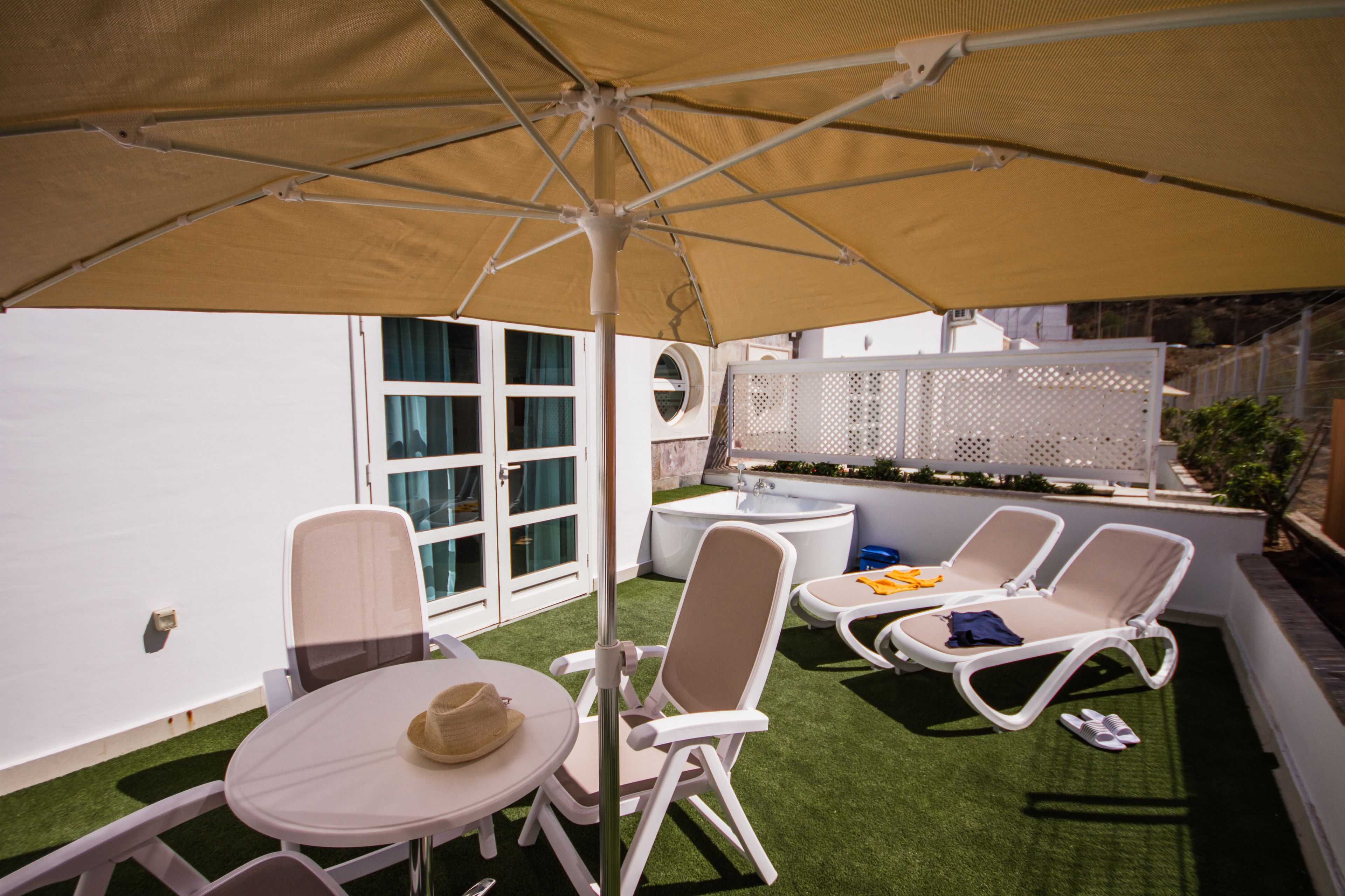 An outdoor patio with a table, chairs, a sun umbrella, and a small pool area.