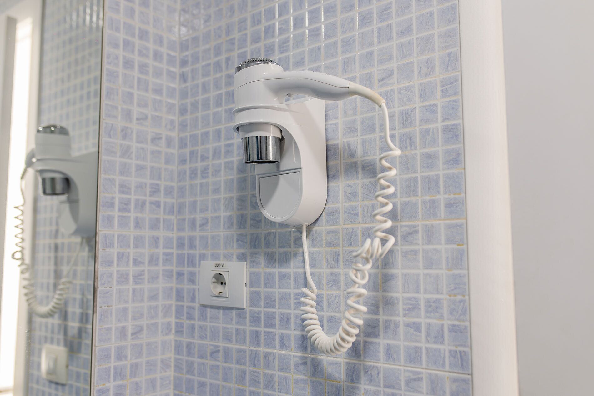 A bathroom with a white telephone mounted on a tiled wall.