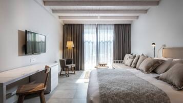 A modern hotel room with a bed, desk, chair, and a TV mounted on the wall.