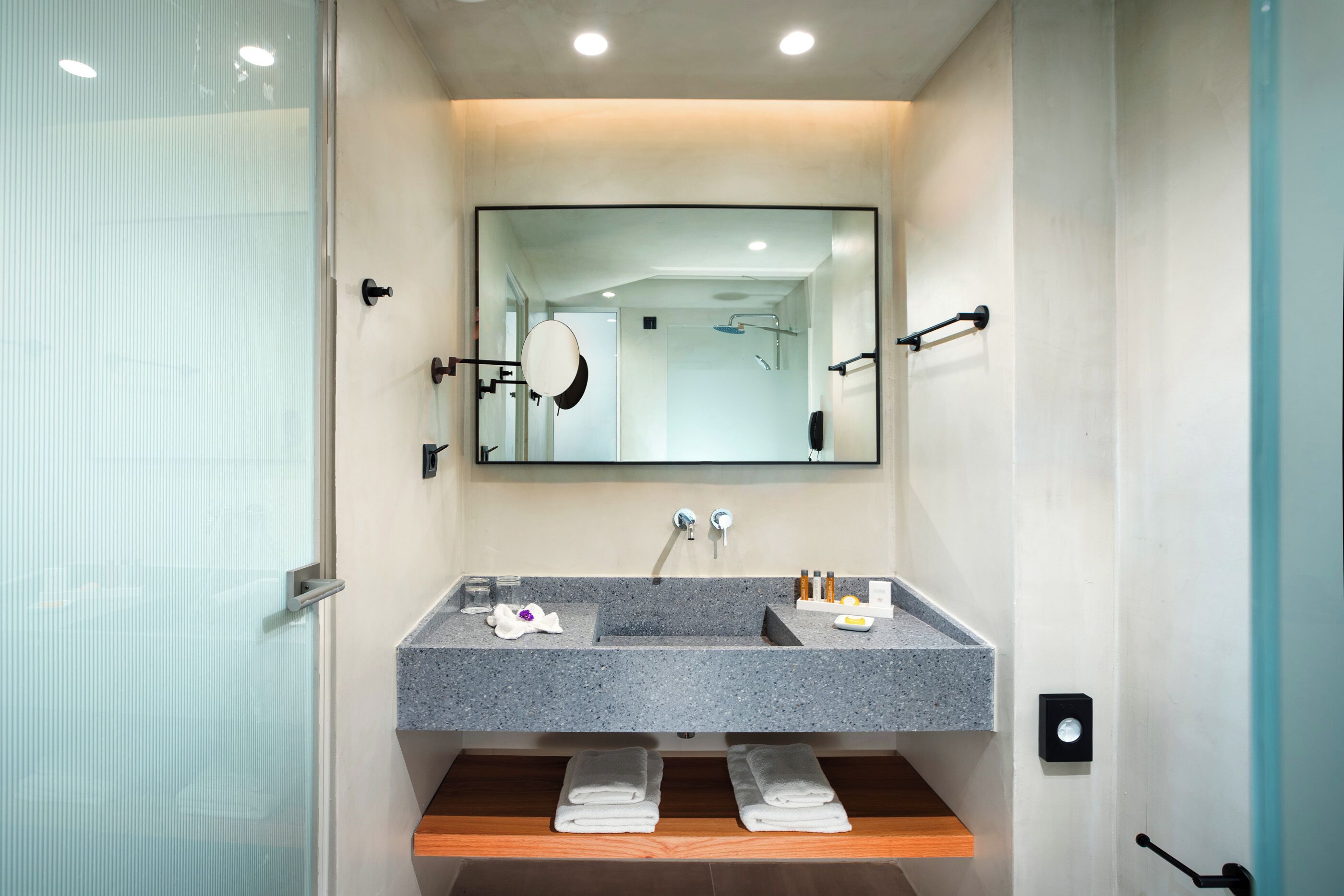 A modern bathroom with a granite sink, a large mirror, and a glass shower enclosure.