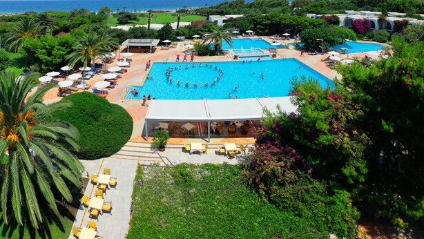 A resort with a large central pool, outdoor seating areas, and a view of the sea. - Caravia Beach Hotel & Bungalows - All Inclusive (Kos)