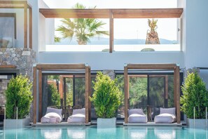 A modern pool area with two seating areas, each with a cushioned bench and a potted plant.