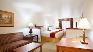A hotel room with a sofa, a bed, a desk, and a lamp.