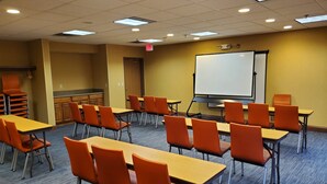 A classroom with tables and chairs, a whiteboard, and a projector screen.