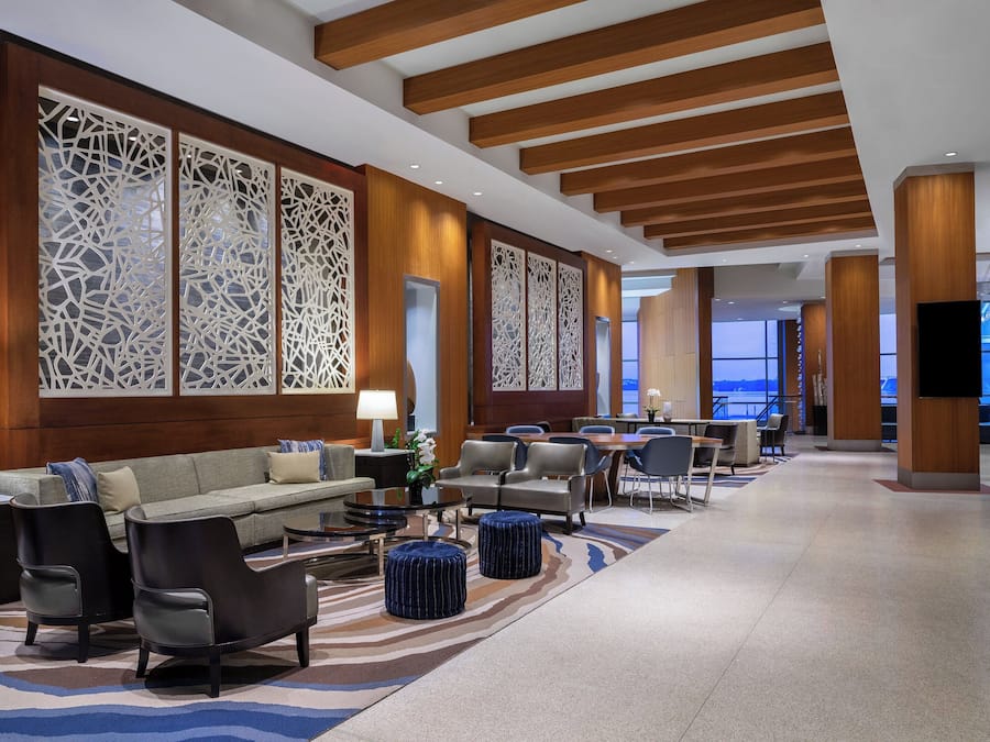 A spacious lobby with a modern design, featuring a sofa, chairs, a coffee table, and decorative screens.