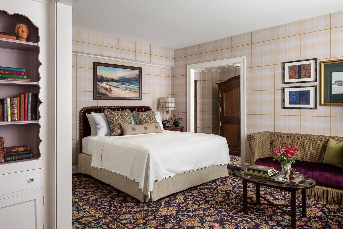 Un dormitorio con una cama grande, un sofá, una mesa de centro y una estantería.