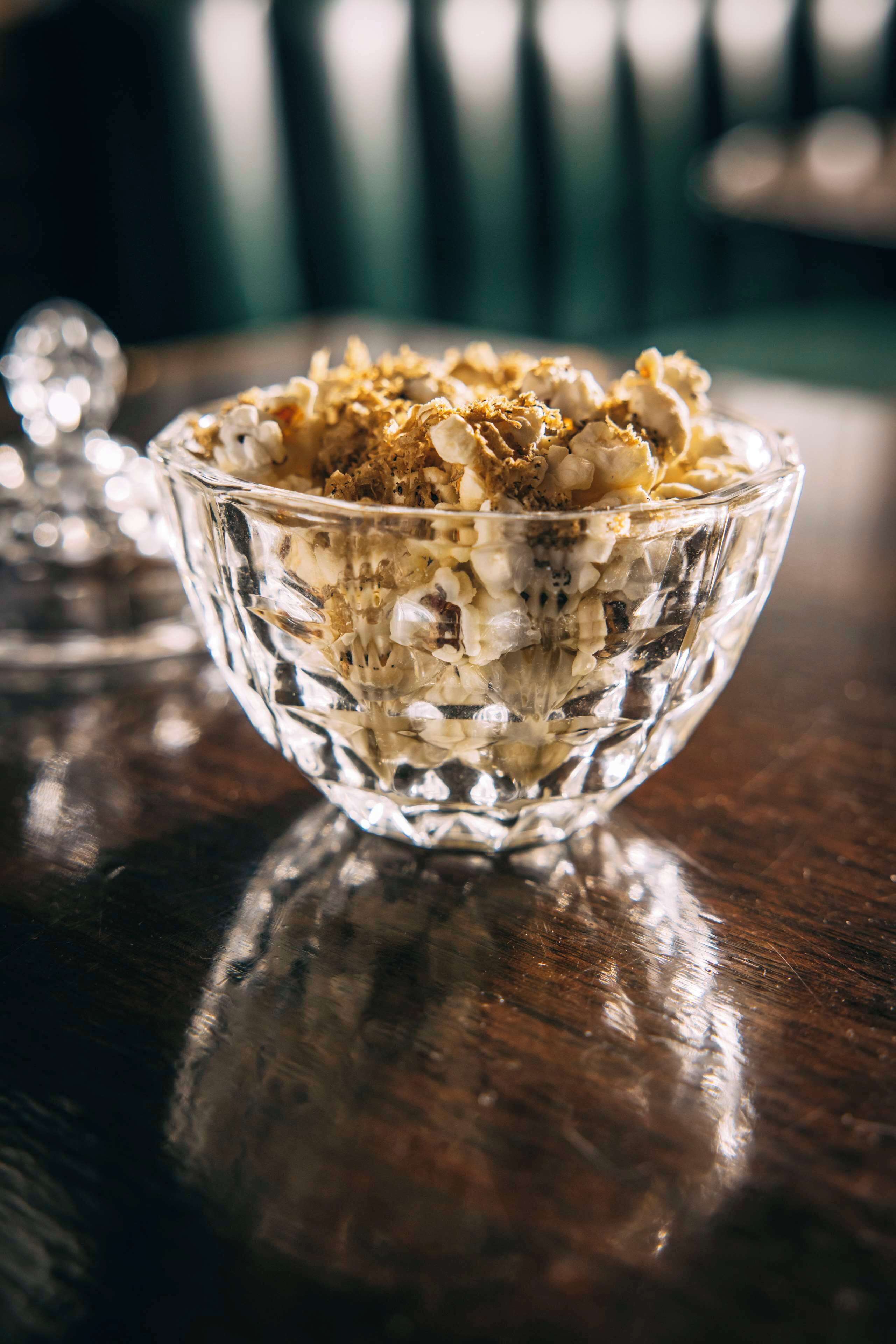 A clear glass bowl filled with granola on a wooden surface.