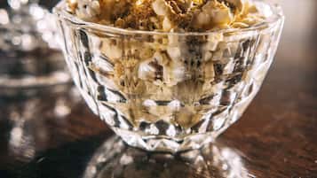 A clear glass bowl filled with granola on a wooden surface.