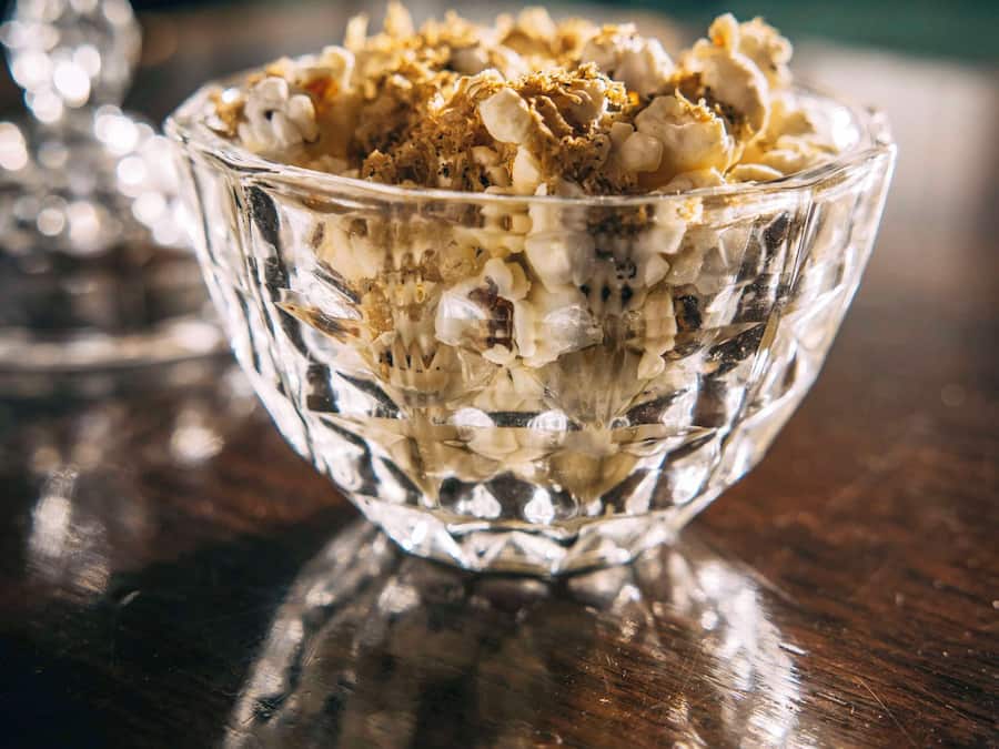 A clear glass bowl filled with granola on a wooden surface.