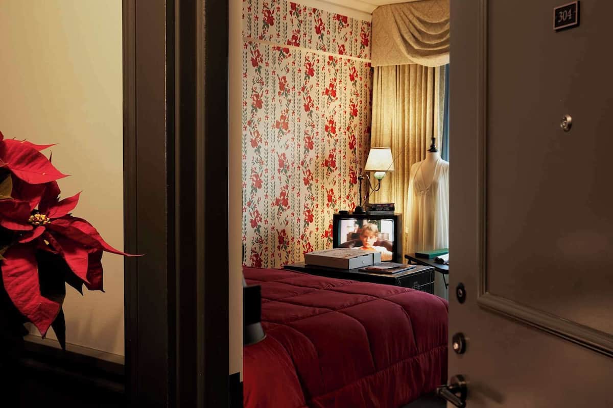 Una habitación de hotel con una cama, televisión y un escritorio con lámpara.